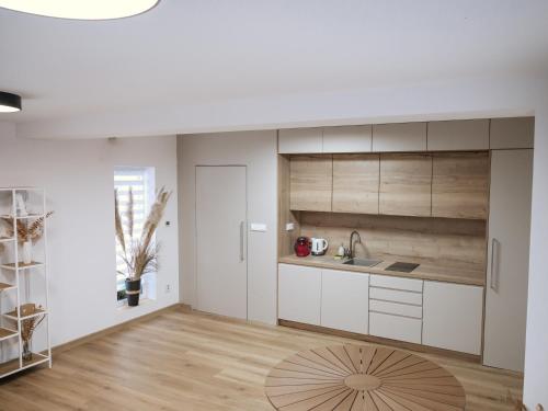 a kitchen with white cabinets and a wooden floor at Ateliér Smutná in Ostrava