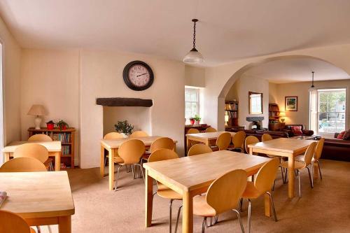 a room with tables and chairs and a clock on the wall at Dol Peris in Llanberis