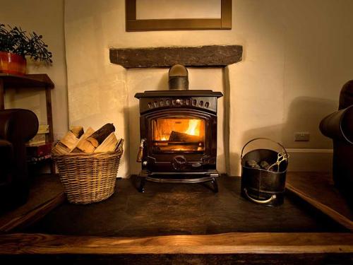 a stove in a living room with a basket of logs at Dol Peris in Llanberis