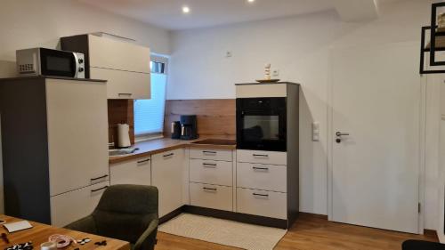 a kitchen with white cabinets and a black refrigerator at Ferienwohnung III Beck-Bräu nahe Bamberg in Trabelsdorf