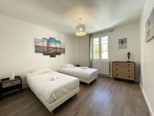 a bedroom with two beds and a dresser and a window at Au bord de l'Eure - Free parking in Chartres