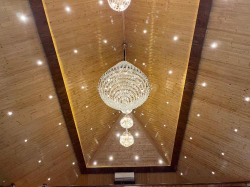 a large chandelier is hanging from a ceiling at The Green Wood Palace I Farm House I wedding I Party I 87oo2o5865 in Gurgaon