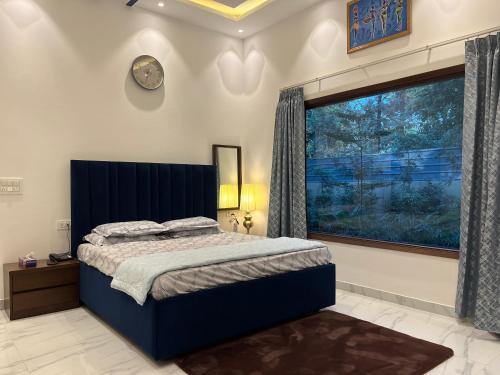 a bedroom with a bed and a large window at The Green Wood Palace I Farm House I wedding I Party I 87oo2o5865 in Gurgaon