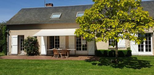 ein Haus mit einem Tisch und Stühlen im Hof in der Unterkunft Le Convivial - Paisible propriété proche ParisChartres in Réclainville