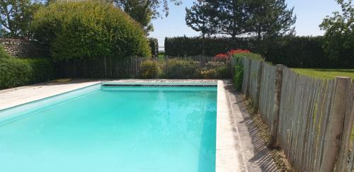 ein blauer Pool neben einem Holzzaun in der Unterkunft Le Convivial - Paisible propriété proche ParisChartres in Réclainville