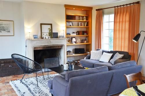 un salon avec un canapé bleu et une cheminée dans l'établissement Le Convivial - Paisible propriété proche ParisChartres, à Réclainville