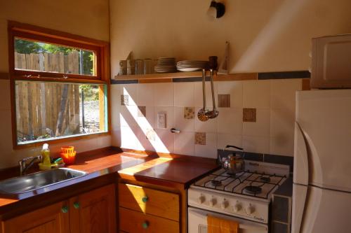a kitchen with a stove and a sink and a refrigerator at Cabañas Las Violetas Patagonia in El Bolsón