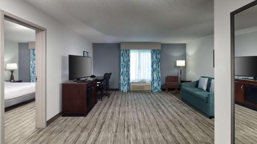 a hotel room with a bed and a couch and a television at Hilton Garden Inn Merrillville in Merrillville