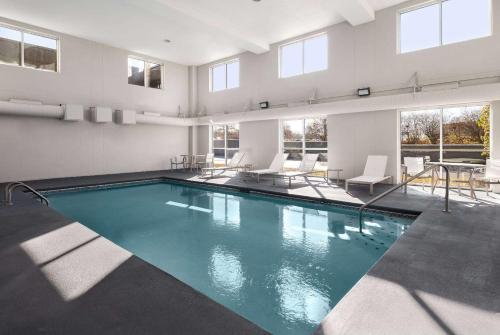 a swimming pool in a building with chairs and a table at La Quinta by Wyndham Knoxville Airport in Alcoa