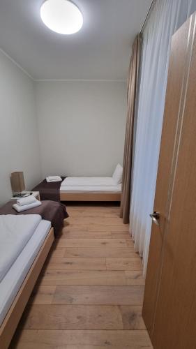 a bedroom with two beds and a wooden floor at Black Pearl Apartments in Jūrmala