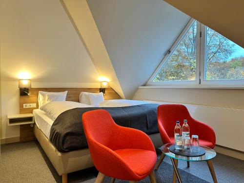 a bedroom with a bed and two red chairs at Hotel Stempferhof in Gößweinstein