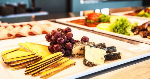 a plate of food with cheese and grapes on a table at Hjorten Hotell Hitra in Fillan
