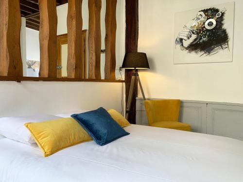 een bed met een geel en blauw kussen erop bij Le Clocher- Appartement dans le cœur de ville in Chartres
