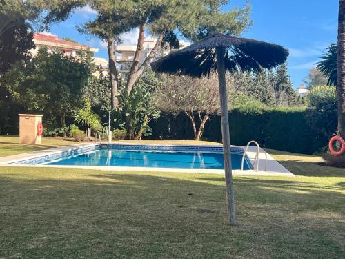 un ombrellone nell'erba accanto a una piscina di Sea view lovely apartment near Puerto Banús a Marbella