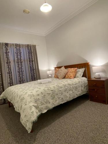 a bedroom with a bed and a dresser and curtains at Home in Church corner in Christchurch