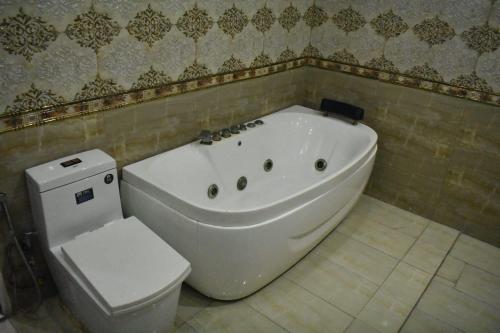 a bathroom with a white tub and a toilet at Grand AlFateh Hotel in Lahore