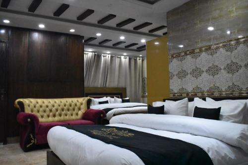 ラホールにあるGrand AlFateh Hotelのベッド4台とソファが備わるホテルルームです。