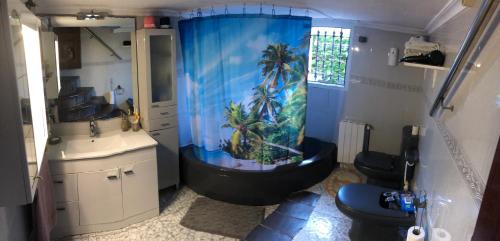 a bathroom with a shower with a palm tree shower curtain at Escuela de Surf Waves Sound in Santoña