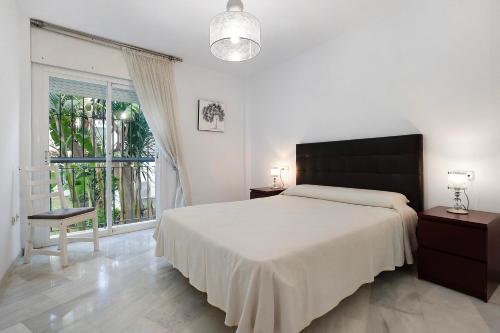 a bedroom with a large bed and a large window at Apartament Don Juan Manuel in Torremolinos