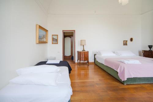 two beds in a room with white walls and wooden floors at B&B Casina de Goyzueta in Torre del Greco