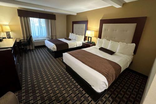 a hotel room with two beds and a desk at AmericInn by Wyndham Woodstock IL in Woodstock