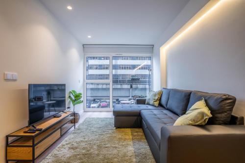 a living room with a blue couch and a television at Trindade Bliss: 1BR w/ Free Parking by LovelyStay in Porto