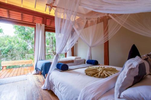 a bedroom with two beds and a large window at Aloha 15 in Ponta Mamoli