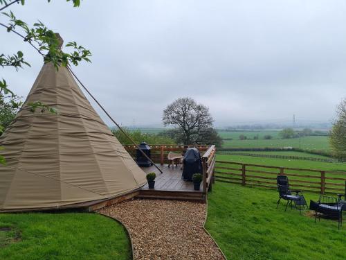 a tent in a field with chairs and a fence at Burtree Country House and Retreats Tipi in Thirkleby