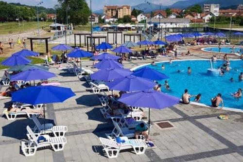 ein großer Pool mit blauen Sonnenschirmen und Menschen darin in der Unterkunft Etno smeštaj Stojadinović in Svrljig