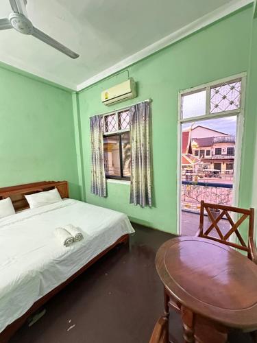 a bedroom with a bed and a table and a window at KFG Guesthouse in Thakhek