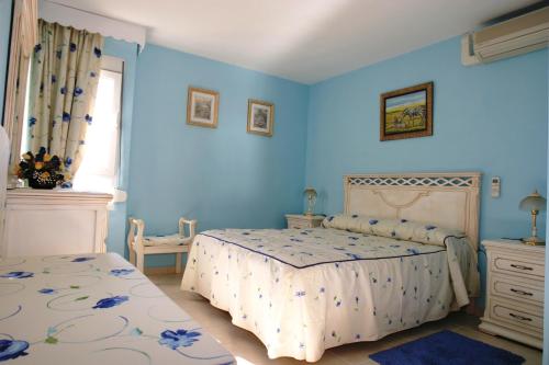 a blue bedroom with two beds and a window at Minerva Jupiter Apartments in Benalmádena