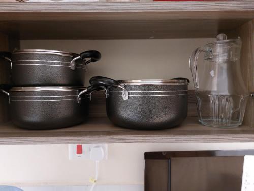 two pots and a pitcher on a kitchen shelf at Rawin Homes in Nyeri