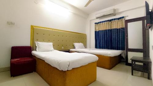 a room with two beds and a chair in it at White Rose Suites Ltd in Dhaka