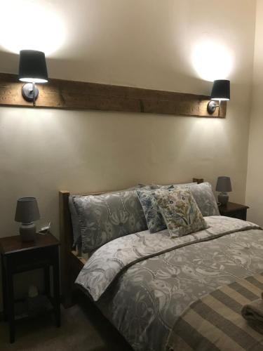 1 dormitorio con 1 cama con 2 luces en la pared en The Nut House - Squirrel Lane Lodges Ludlow, en Ludlow