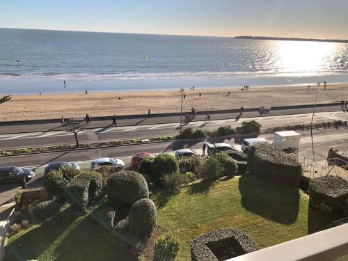 - une vue sur une plage avec des voitures garées à côté de l'océan dans l'établissement Splendide et spacieux appartement, face à la mer, à La Baule