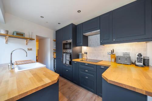 a kitchen with navy blue cabinets and a sink at Charming Cornish Cottage in the heart of St Agnes in St. Agnes