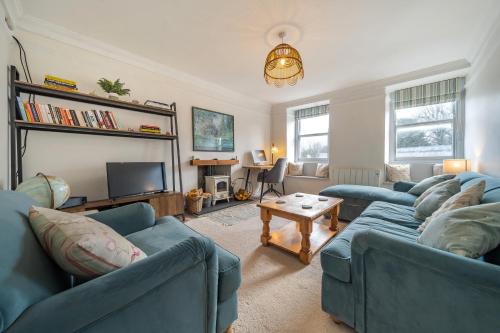 a living room with two blue couches and a tv at Charming Cornish Cottage in the heart of St Agnes in St. Agnes 