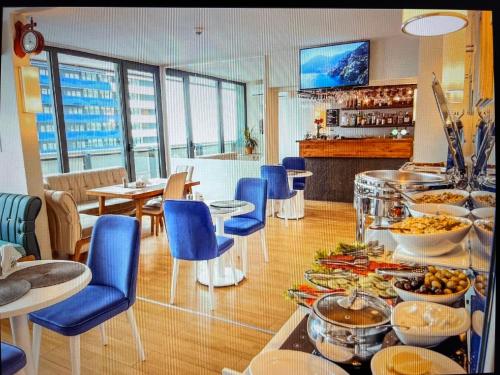 un ristorante con sedie blu e un buffet di cibi di Panorama Sea View Central City Batumi & ApartHOTEL a Batumi