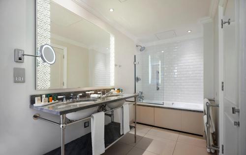 a bathroom with a sink and a tub and a mirror at The Waldorf Hilton in London