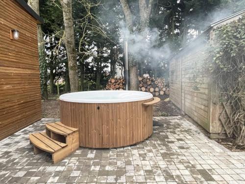 d'un bain à remous dans un jardin avec un banc dans l'établissement L'Echappée au Gué - Nordic bath, à La Fontenelle