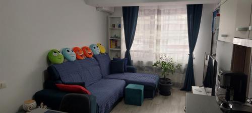 ein Wohnzimmer mit einem blauen Sofa und bunten Kissen in der Unterkunft LittleBIG Apartment in Bukarest