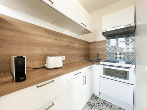 cocina con armarios blancos y paredes de madera en The Châtelet, en Chartres