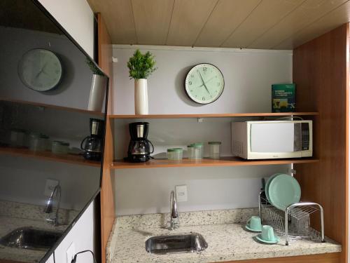 uma cozinha com um lavatório e dois relógios na parede em SUÍTE independente com Ar, Wifi, Smartv e Cozinha em Macaé