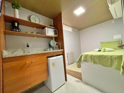 a small bedroom with a bed and a counter at STUDIO aconchego, com Ar, Wifi, Smartv e Cozinha in Macaé
