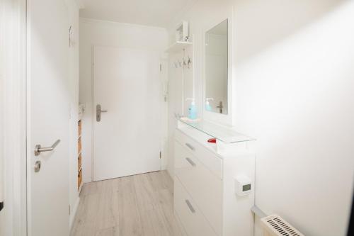 a white bathroom with white cabinets and a mirror at Aurora in Norderney