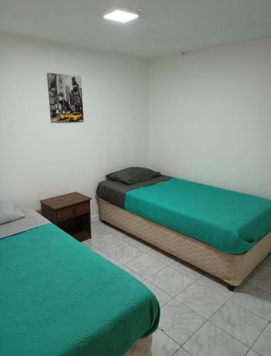 two beds in a room with green sheets at Hospedaje GYT Caldera in Caldera