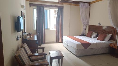 um quarto de hotel com uma cama e uma televisão em Suhufi Palace Hotel em Mombaça