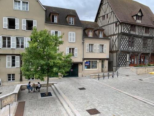 dwoje ludzi siedzących na ławce przed budynkiem w obiekcie Le tertre Chartrain - Maison de ville en plein centre de Chartres w mieście Chartres