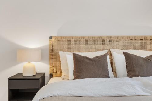 Bett mit Kissen und Tisch mit Lampe in der Unterkunft Flott leilighet i hjerte av Oslo in Oslo