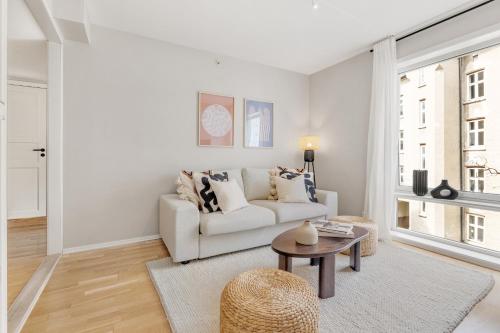 ein weißes Wohnzimmer mit einem Sofa und einem Tisch in der Unterkunft Flott leilighet i hjerte av Oslo in Oslo